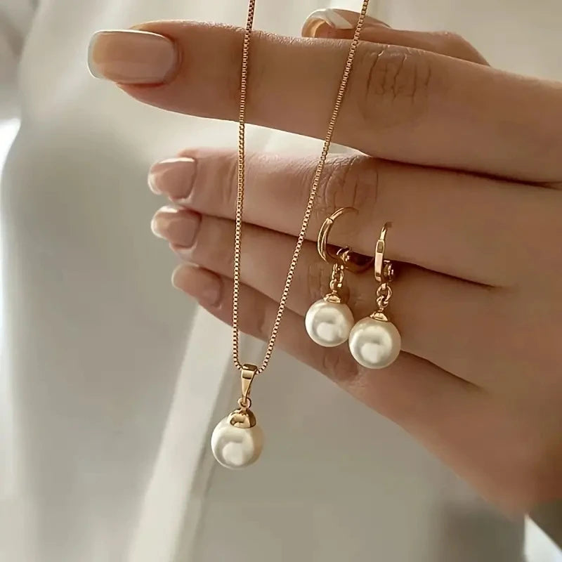 Vintage gold pearl pendant necklace and matching pearl drop earrings held in hand