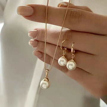 Vintage gold pearl pendant necklace and matching pearl drop earrings held in hand