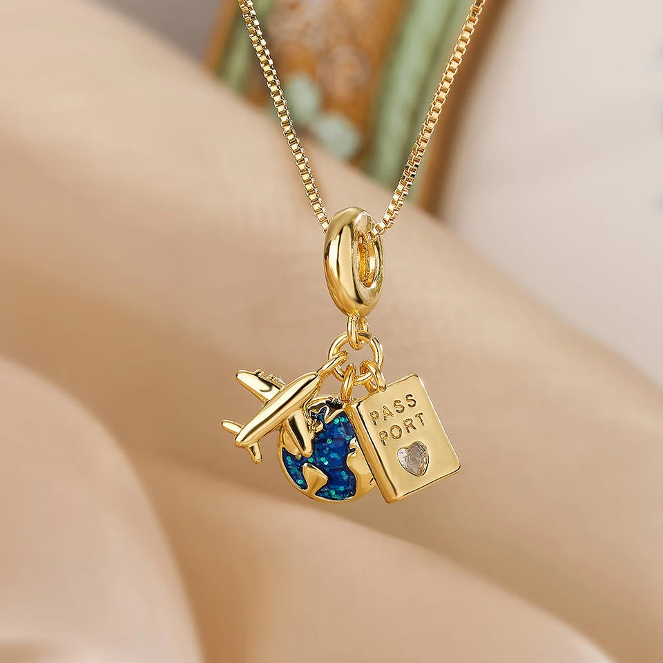 Gold-tone travel charm necklace with airplane, blue globe and passport charms