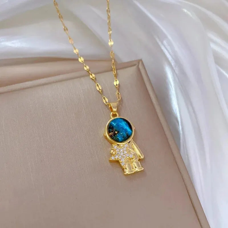 Gold-tone astronaut pendant necklace with a blue planet stone on a white backdrop