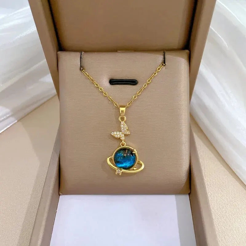 Gold-tone Saturn style planet pendant necklace with a blue stone in a gift box