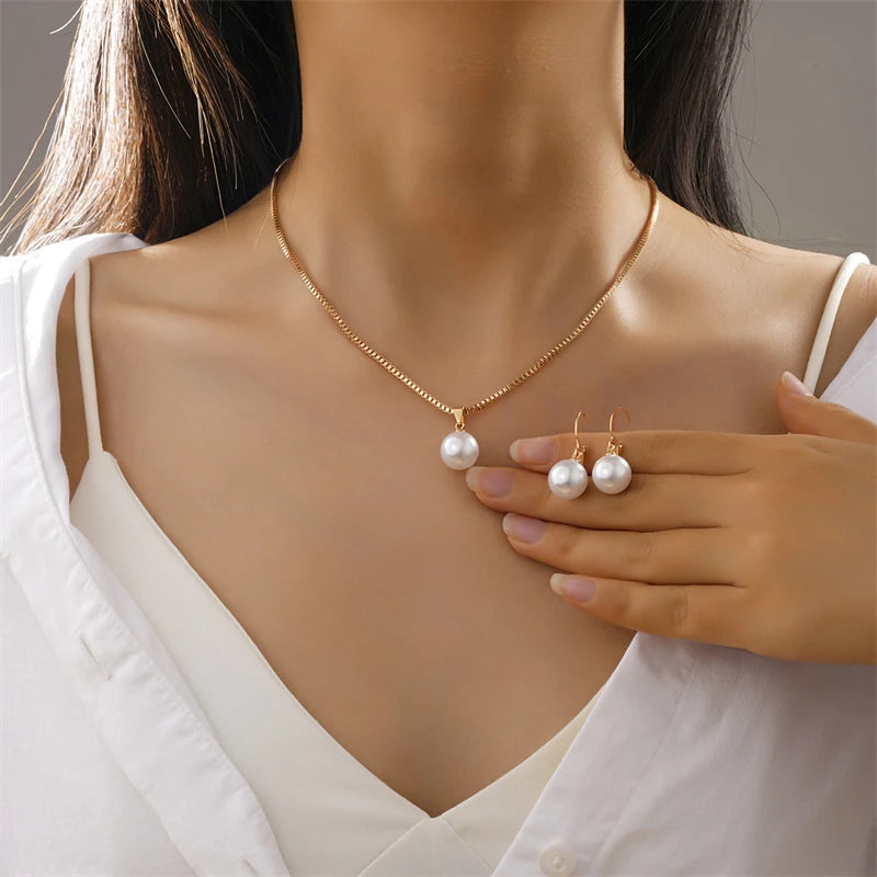 Woman wearing the vintage gold pearl pendant necklace with matching pearl drop earrings