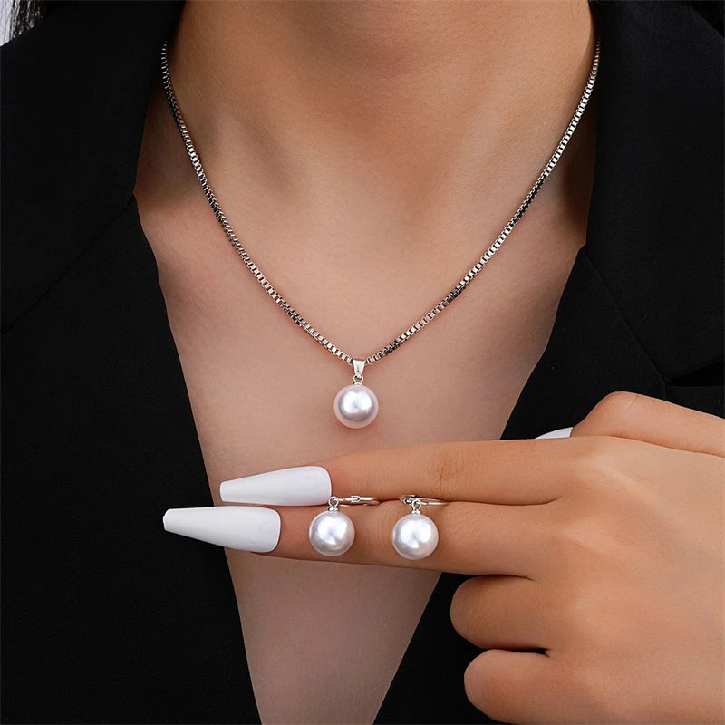 Woman wearing the silver tone pearl pendant necklace and holding the matching earrings