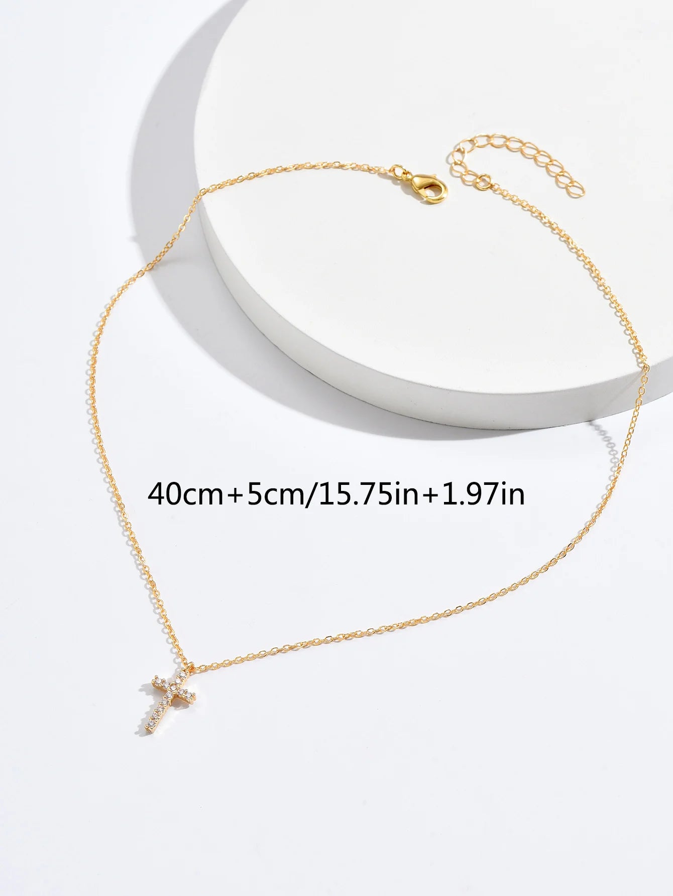 Size guide image showing the cross necklace measures 40 cm plus a 5 cm extender, 15.75 in plus 1.97 in