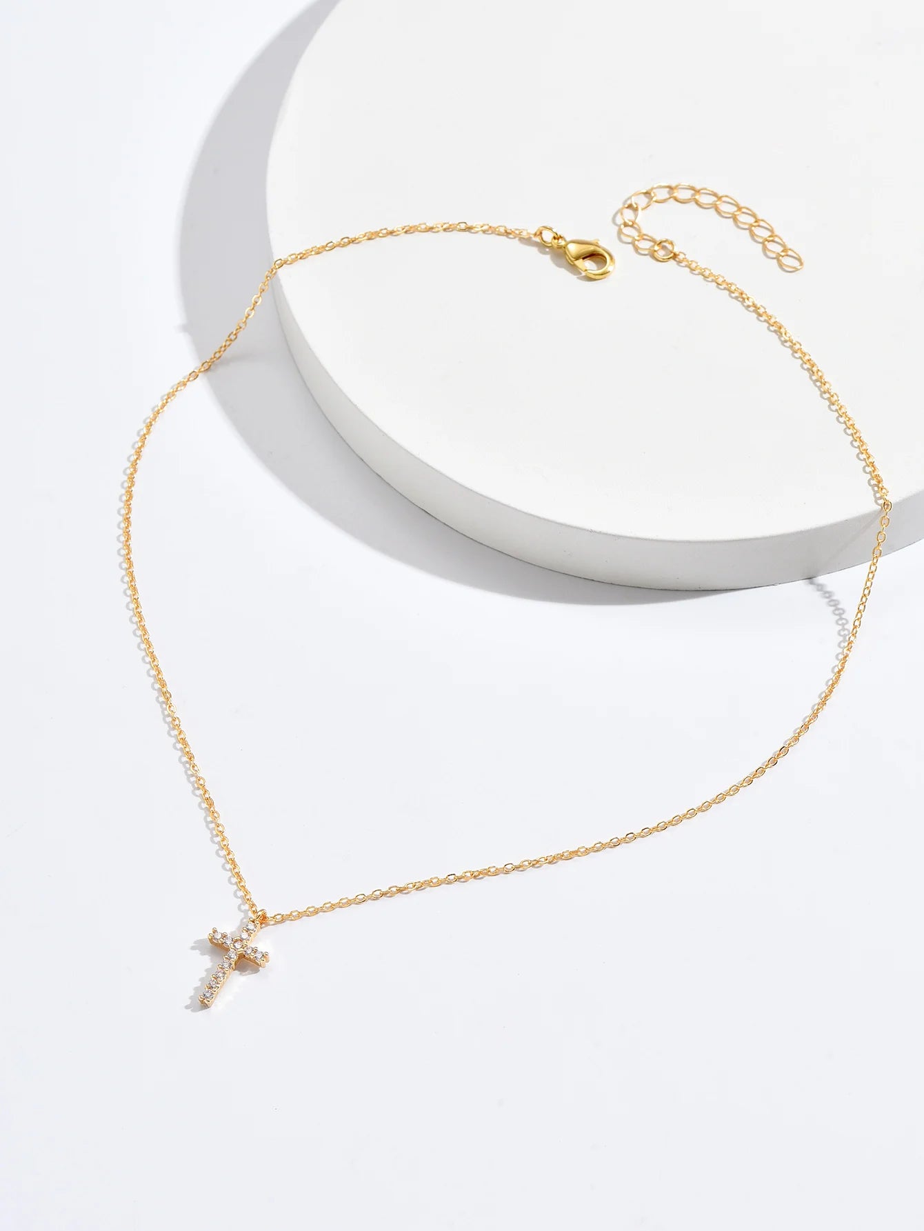 Full gold-tone cross necklace laid flat, showing the lobster claw clasp and extender chain