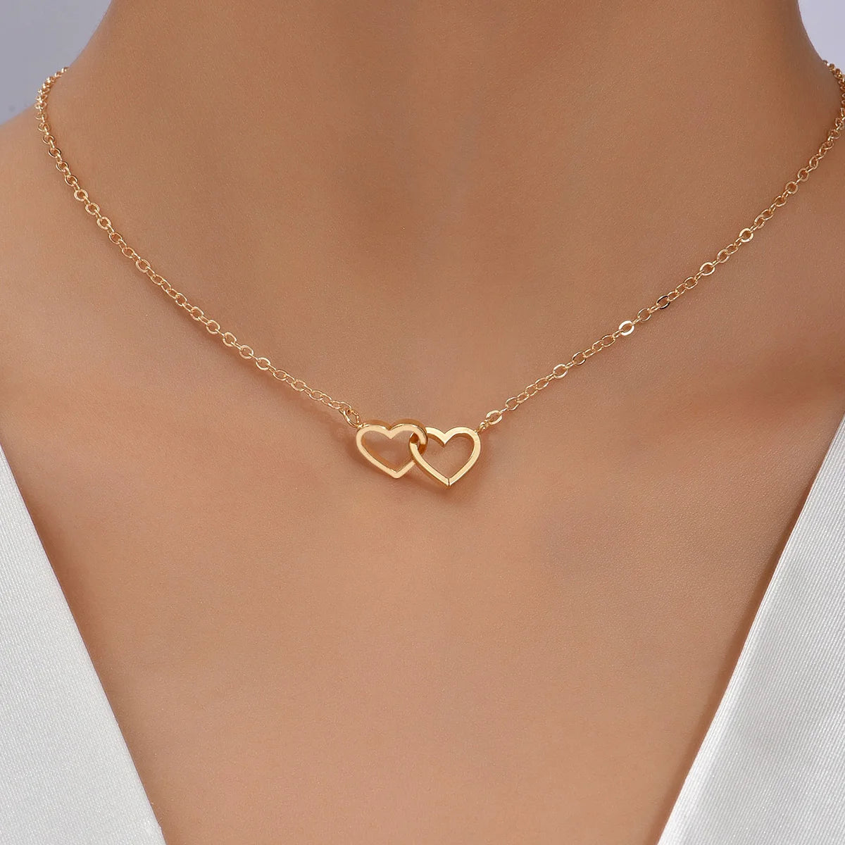 Gold-tone double heart necklace worn close-up on a woman's neck