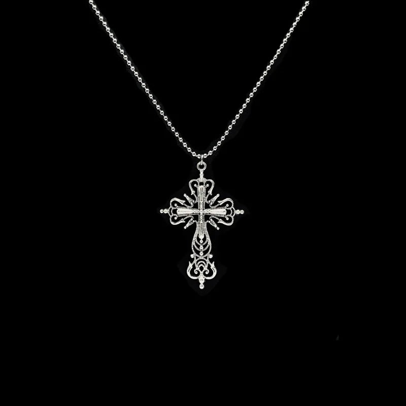 Ornate silver cross pendant necklace on a ball chain photographed against a black background