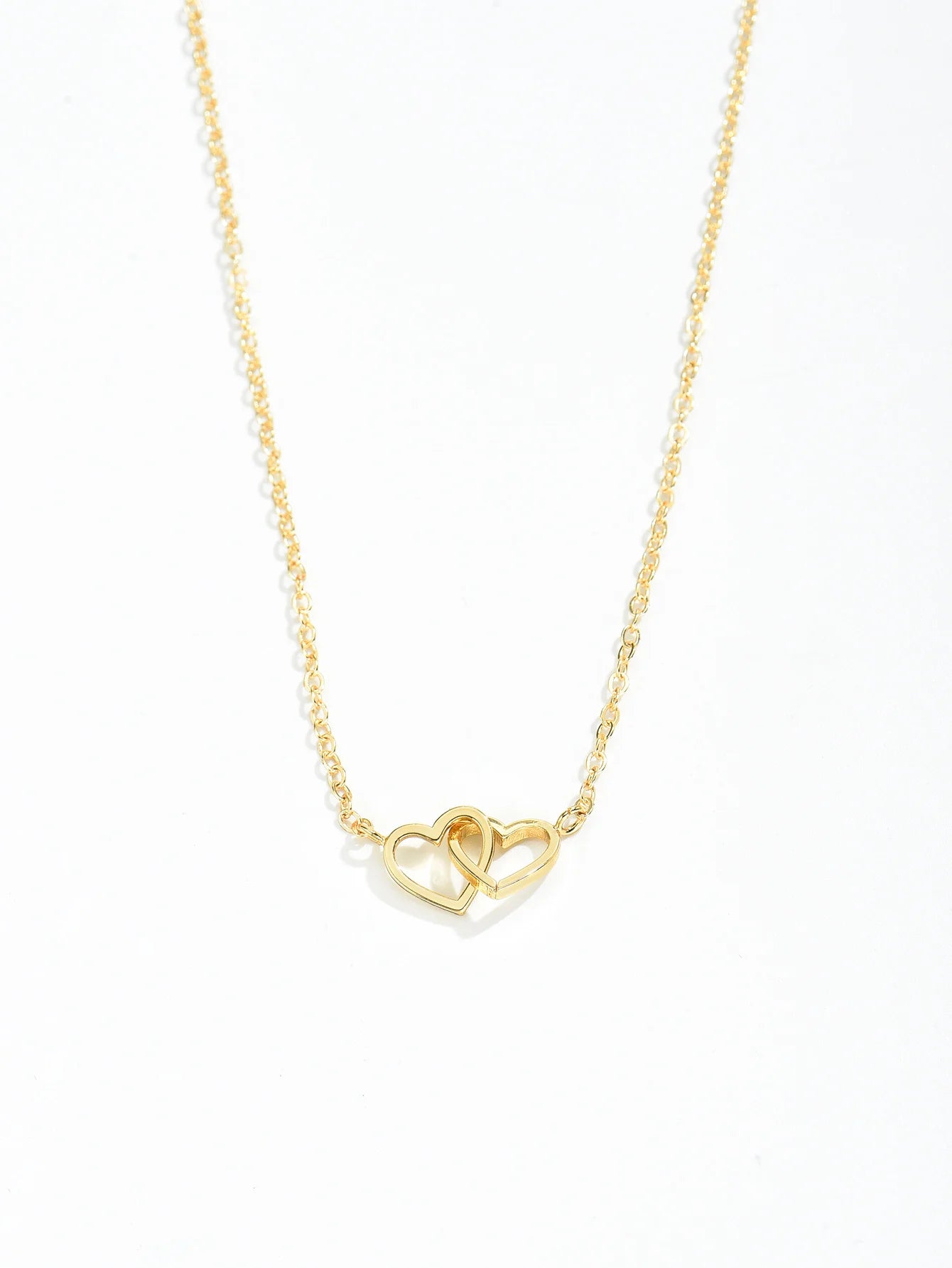Close-up of the hollow interlocking heart pendant on a gold-tone link chain
