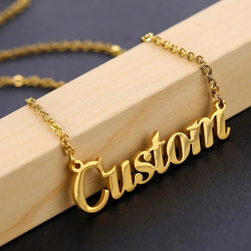 Gold-tone stainless steel name necklace spelling Custom on a wooden block