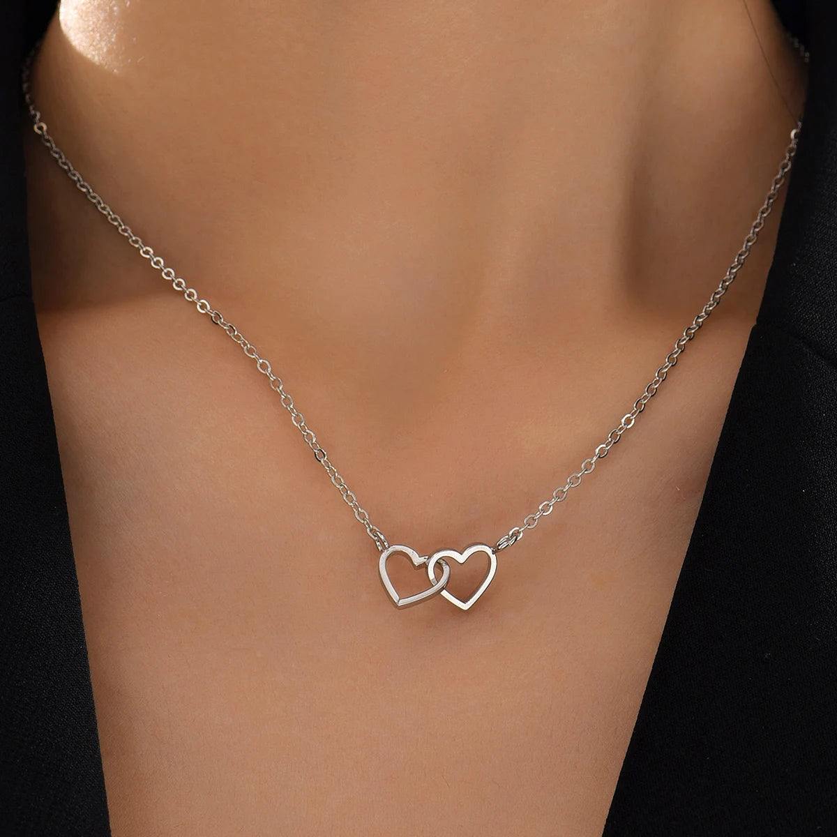 Silver-tone double heart pendant necklace styled against a black top