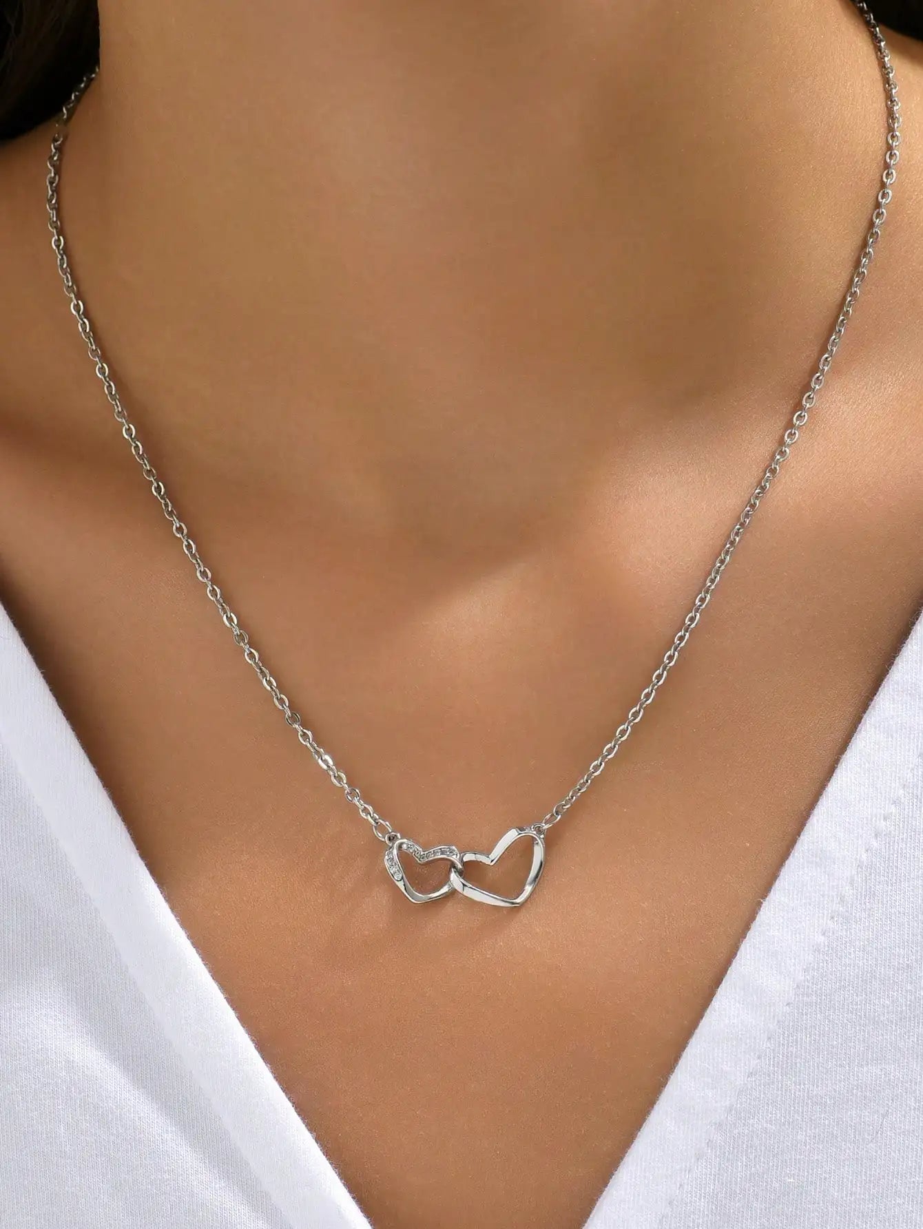 Silver-tone version of the double heart necklace worn with a white V-neck top